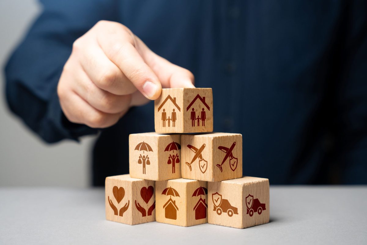 homme en costume posant des cubes représentant diverses assurances.