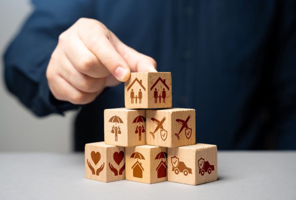 homme en costume posant des cubes représentant diverses assurances.